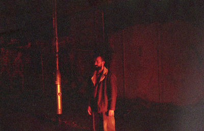 Full length of man standing against illuminated wall at night