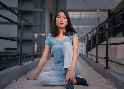 A beautiful woman in a blue shirt sat casually while staring at the camera