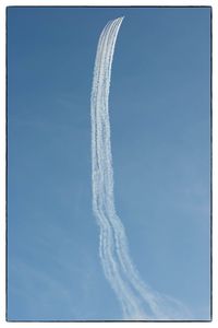 Low angle view of vapor trail against clear blue sky