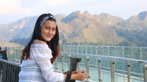 Portrait of smiling woman standing on railing