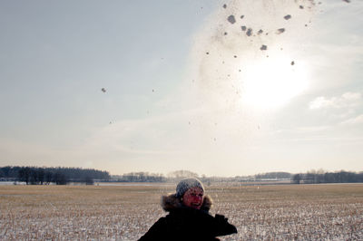 Woman flying over field against sky