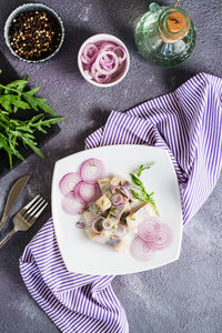 Sliced salted herring in oil with onion and dill on a plate on the table. simple snack. 