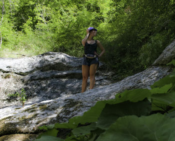 Full length of young woman standing by rock