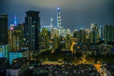 Illuminated modern buildings in city against sky at night