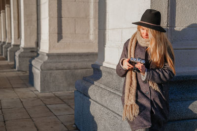 Full length of woman using mobile phone in city