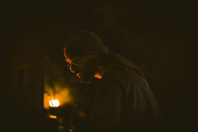 Portrait of young man in illuminated dark room