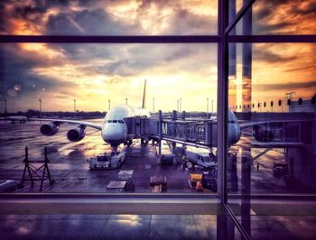 Airplane on airport runway against sky during sunset