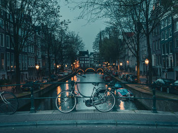 Bicycle parked by railing against buildings in city