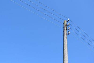 Low angle view of cables against clear blue sky