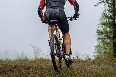 Rear view of man riding bicycle on field