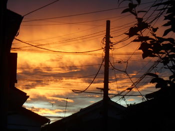 Low angle view of electricity pylon against cloudy sky