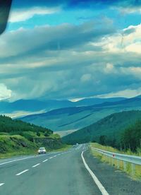 Road leading towards mountains against sky