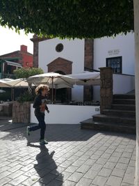 Woman on footpath amidst buildings in city