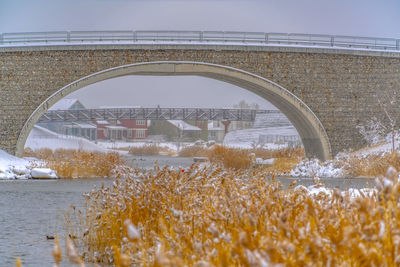 Arch bridge over river against clear sky during winter