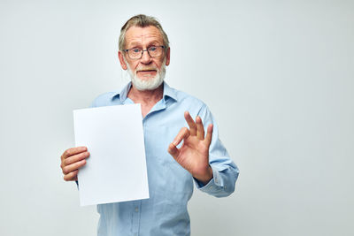 Portrait of senior man showing document