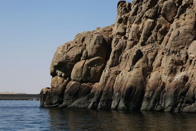 Rock formation in sea against clear sky