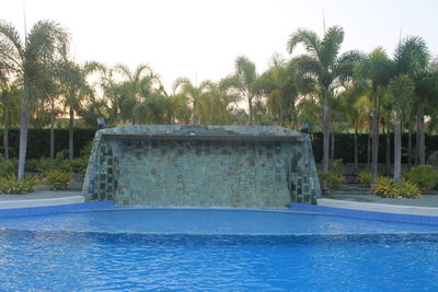 Swimming pool by trees against sky