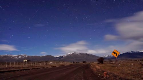 Road by mountains against sky at night