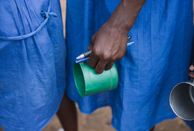 Midsection of woman holding mug and pens while standing in queue