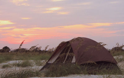 Tent on field against sky during sunset