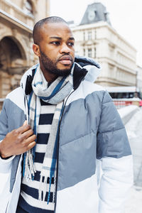 Young african man on street, snow winter season, city portrait