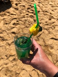 Midsection of person holding drink on sand