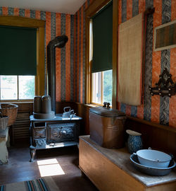 An old stove in a house entryway along with wash basins and old wallpaper.