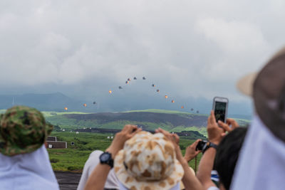 People photographing against cloudy sky
