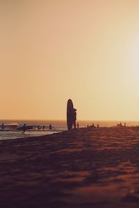 Silhouette people on beach against clear sky during sunset