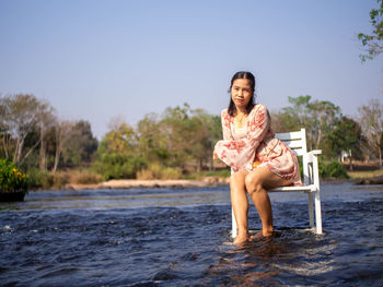 A woman sitting in a chair in the middle of the river
