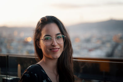 Portrait of smiling young woman against sky