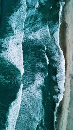 High angle view of sea waves splashing on rocks