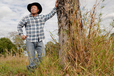 Farmer man in shirt and cowboy hat looking at camera happy close up standing at the farm