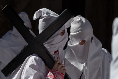 Penitentes holding cross while standing on street