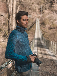 Young man looking away while standing on footbridge