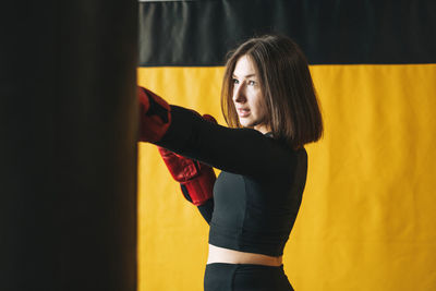 Young brunette woman in black wear engaged boxing training in the fitness club gym