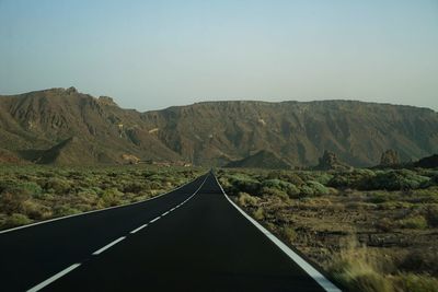 Road leading towards mountains against sky