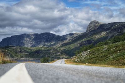Empty road by mountains against sky