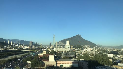 High angle view of buildings in city against clear blue sky