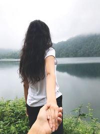 Close-up of man holding hand of woman by lake