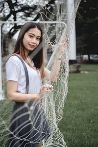 Portrait of smiling young woman standing in goal post