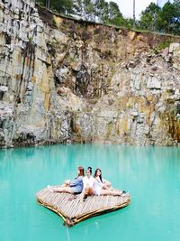 People relaxing on rock by water