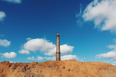 Low angle view of abandoned smoke stack on industrial site against sky