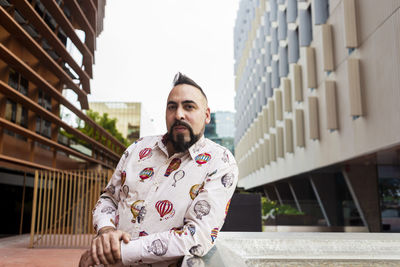 Bearded man standing and relaxing on stairs against office building