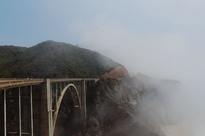 Arch bridge over mountains against sky