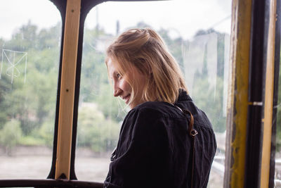 Side view of young woman looking through window