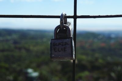 Close-up of padlocks on railing against sky