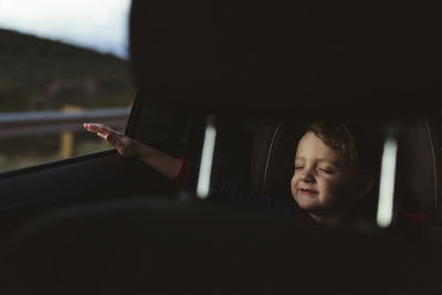 Cute boy with eyes closed enjoying road trip seen through vehicle seat