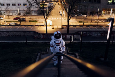 Female astronaut standing on staircase near road at night