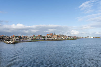 Sea by buildings against sky in city